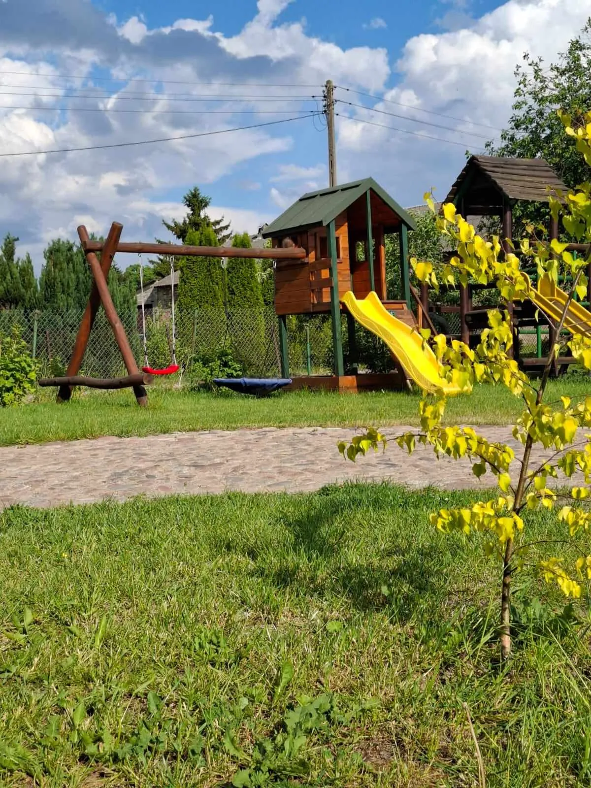 Drewniany plac zabaw z domkiem i zjeżdżalnią